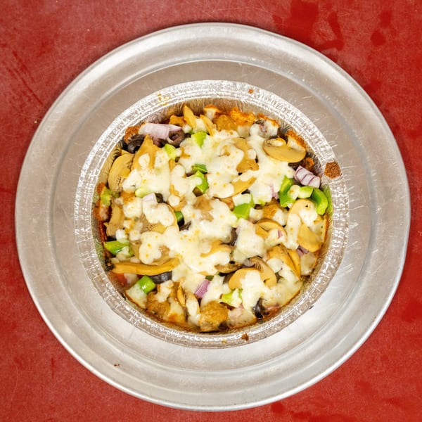 Baked dish with melted cheese, mushrooms, green peppers, red onions, and olives in a foil pan.