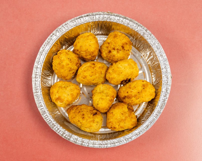 Ten golden-brown fried nuggets in a round silver foil container.
