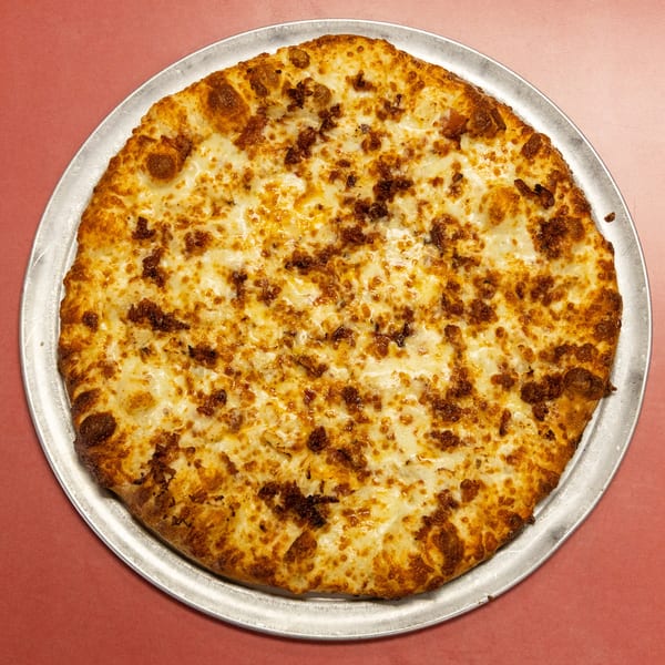 Whole round pizza with melted cheese and savory brown crumbles on a metal pan.